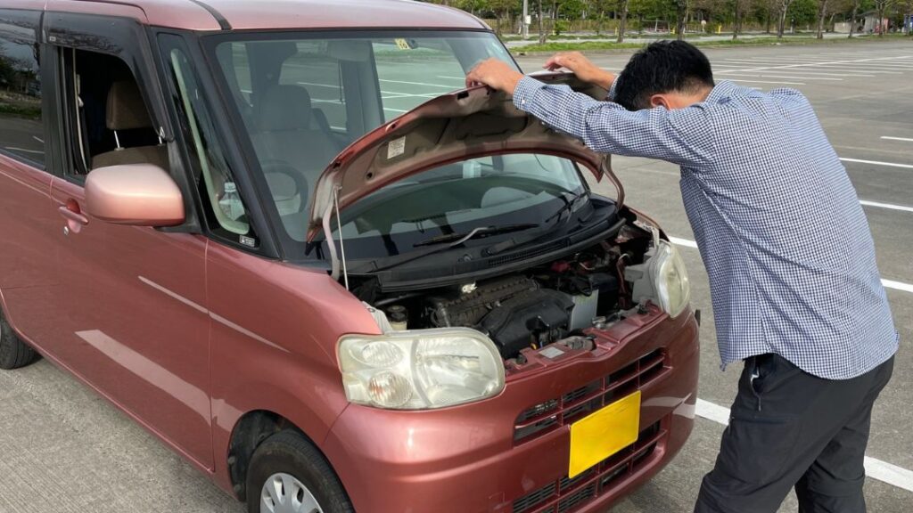 コラム画像 | 車買取のソコカラ 車が水漏れしており、原因を調べるためにボンネット開けている男性