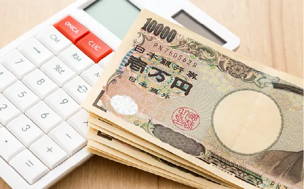 Stack of Japanese yen banknotes fanned on a white calculator, suggesting money calculation.